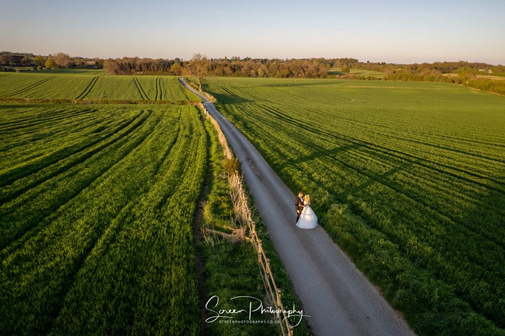 Aerial drone picture of married couple on Swancar Farm Country House long driveway in golden sun hour