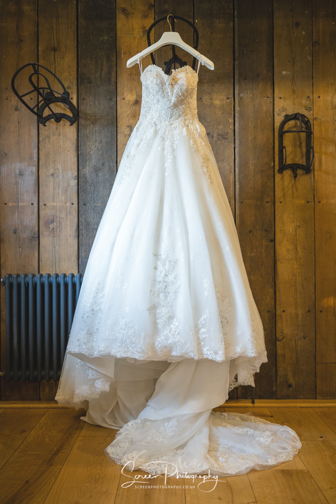 Clock Barn wedding venue Hampshire dressing room bridal wedding dress hanging from horse saddle