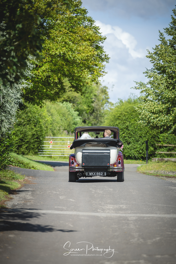 The Clock Barn wedding venue Hampshire Berkshire vintage classic car driving off with married couple bride groom