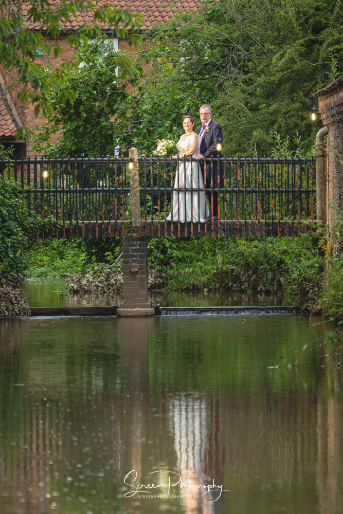 The Mill Hoveringham wedding barn water mill venue married bride groom on brick bridge reflecting