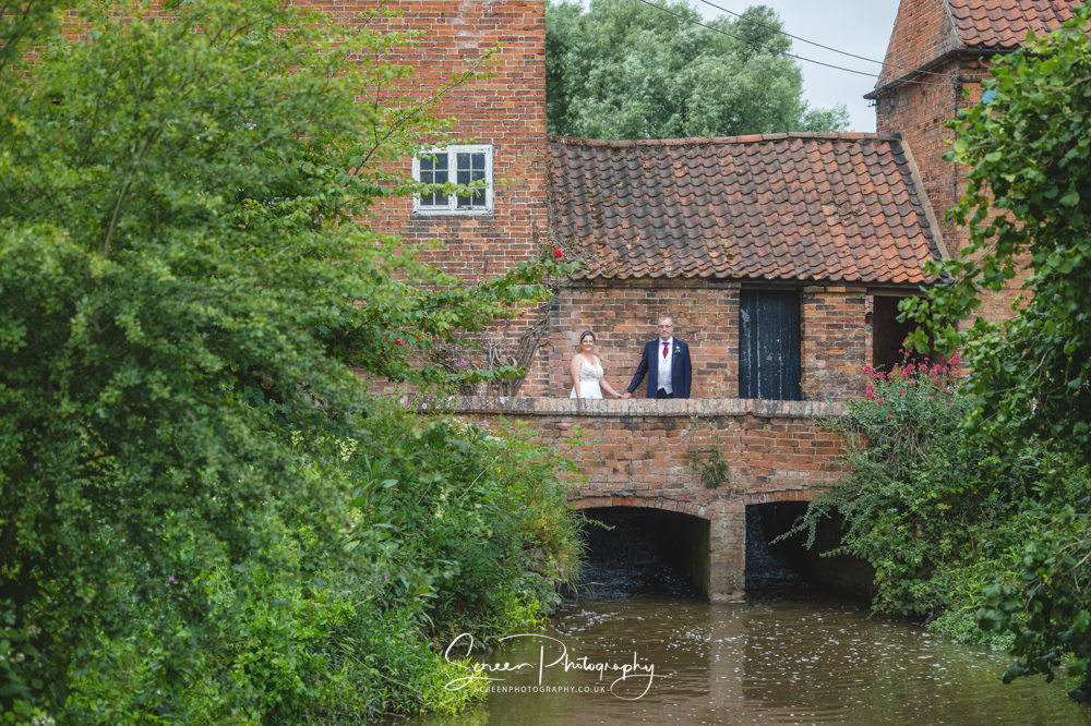 The Mill Hoveringham wedding barn watermill venue with water for married photos dog pet friendly DIY weddings couple on bridge holding hands