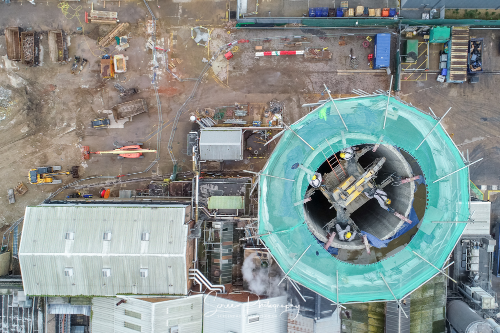 construction drone nottingham looking down on high rise chimney with construction workers and digger