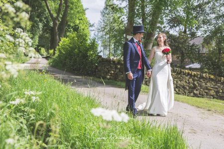 darwin lake wedding photography bride groom in top hat tails walking along country lane in the peak district