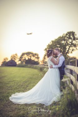 Donington Park Farmhouse wedding venue Leicestershire married couple bride groom at sunset in field with aeroplane above
