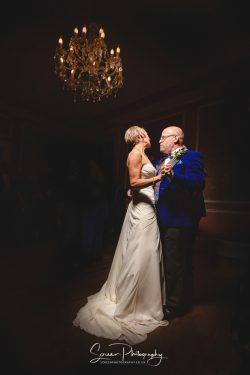 married couple first dance under chandelier black tie wedding dress Penton Park Hampshire