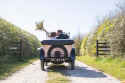 stretton manor barn wedding photography bride groom in vintage car driving away with flowers in air