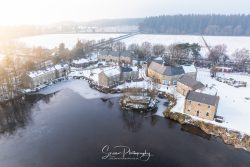 commercial drone nottingham of peak district winter wintry scene of holiday cottages in the snow at sunset