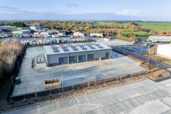 commercial drone nottingham of large garage services building with industrial buildings around and forest in the distance