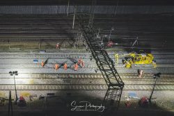 commercial drone photography showing over head electrified train lines with rail workers during the dark night hours Willesden junction london