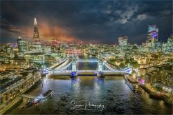 commercial drone-photography showing tower bridge at night with the shard and other famous landmarks over the river thames