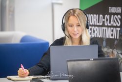 commercial photography nottingham lady working at laptop in office holding pen and talking through a headset
