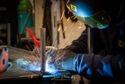 commercial photography nottingham with a man welding metal sparks flying up and wearing mask